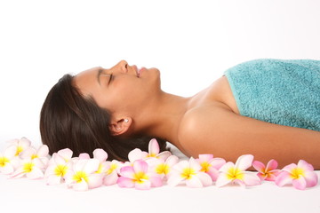 Young woman relaxing in health spa amongst frangipani flowers
