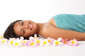 Obraz na płótnie Canvas Smiling young woman in health spa amongst tropical frangipanis
