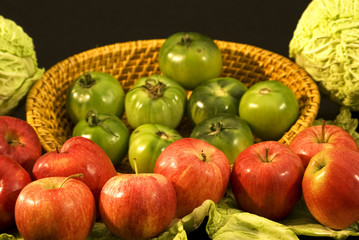 Cesto con pomodori verdi, mele rosse e cavoli