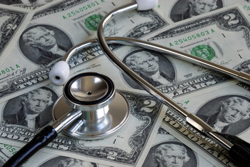 A stethoscope on the top of some two dollar bills