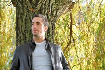 Young man leaning against a willow tree