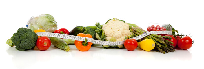A row of vegetables and a tape measure on white