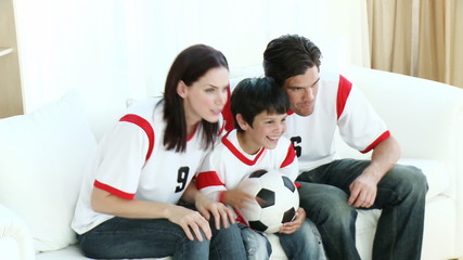 Family in Living Room watching fooyball of TV