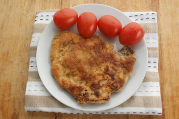 cutlet with organic tomato on a white plate