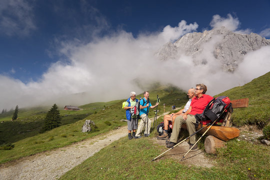 senior hikers at short break on bench in beautiful mountains