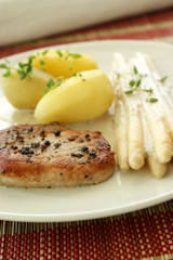 pork chop with potato and asparagus on a plate