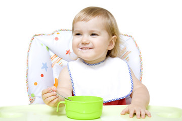 Smiling little girl sitting in baby chair and eating