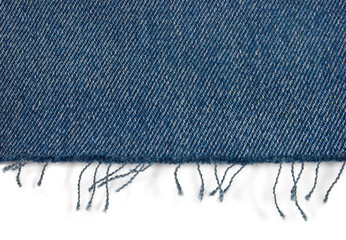 Edge of blue jeans fabric with fringe