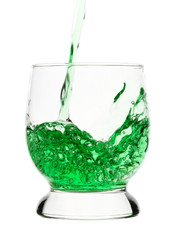 Green drink is being poured into glass