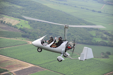 Autogyro flying over the tropical landscape
