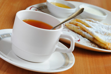 Tea and pancakes  with powdered sugar