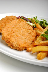 breaded fish steak with organic salad on a plate