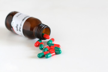 A open pill bottle, with capsules spilling from it.