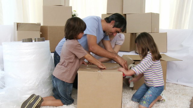 Parents and children moving house packing boxes