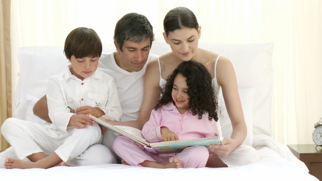 Family reading a book on bed