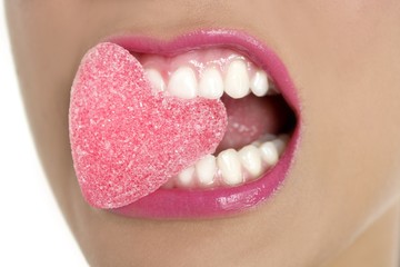 Naklejka premium Heart shape candy on woman macro mouth