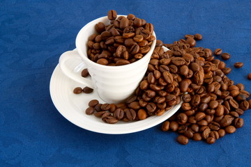 cup with coffee and grain expressed on blue background