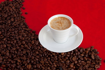 cup with coffee and grain expressed on red background