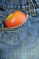 Front blue jeans pocket holding an apple