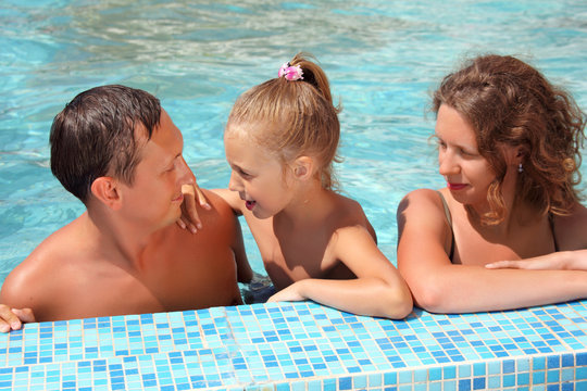 Happy family with little girl bathe in pool