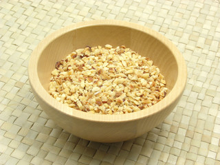 Holzschale mit gerösteten Haselnüssen auf Rattan