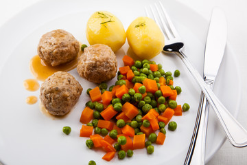 Roasted meatballs with boiled potatoes, peas and carrot