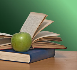 Green apple and books on desk