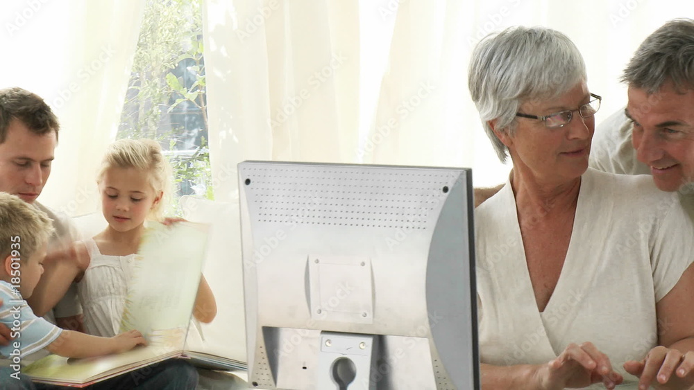 Wall mural Family at home using a laptop and reading a book