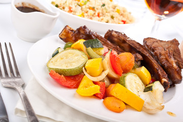 barbecue spare ribs on a plate with vegetables and couscous
