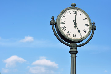 The big figured street clock against the blue sky