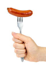 Hand holding grilled sausage on the fork