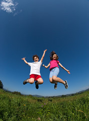 Fototapeta na wymiar Kids running, jumping on green meadow