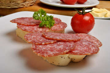 slice poppy seed bread with salami on a plate