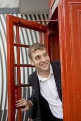 man inside traditional English red telephone box