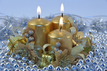 Obraz na płótnie Canvas Three golden burning candles with Christmas decorations