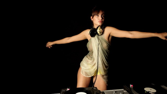beautiful young female dj, behind the decks at a club
