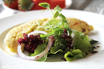Delicious salad with omelette on white plate.