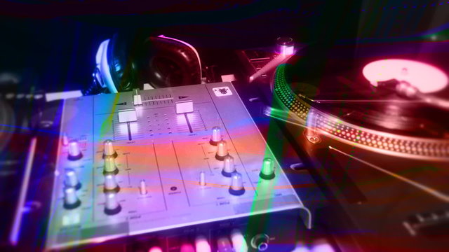 a pan across dj turntables with abstract light patterns