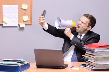 Angry businessman in an office, shouting on a megaphone