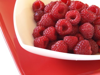 Raspberries on the red and white plate.