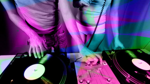 dj scratches records with girl next to him