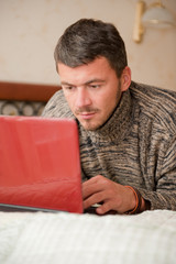 Young handsome man working from his home on laptop