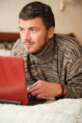 Young handsome man working from his home on laptop
