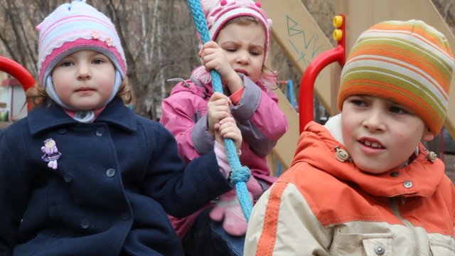3 kids playing on monkey bars
