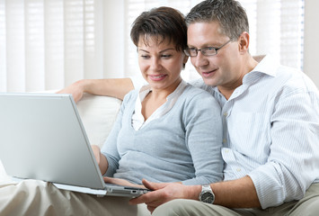happy couple using laptop at home