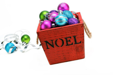 Christmas ornaments in a wooden box with NOEL stenciled on the front.