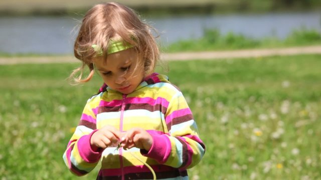 Girl in purple blouse plays with dandelion. Greenfield, river
