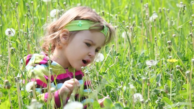 Little girl sitting on green field looking to the right