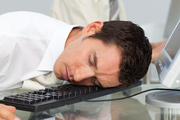 Businessman sleeping on the keyboard in the office