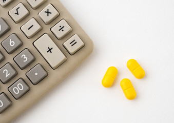 Calculator and pills on white background